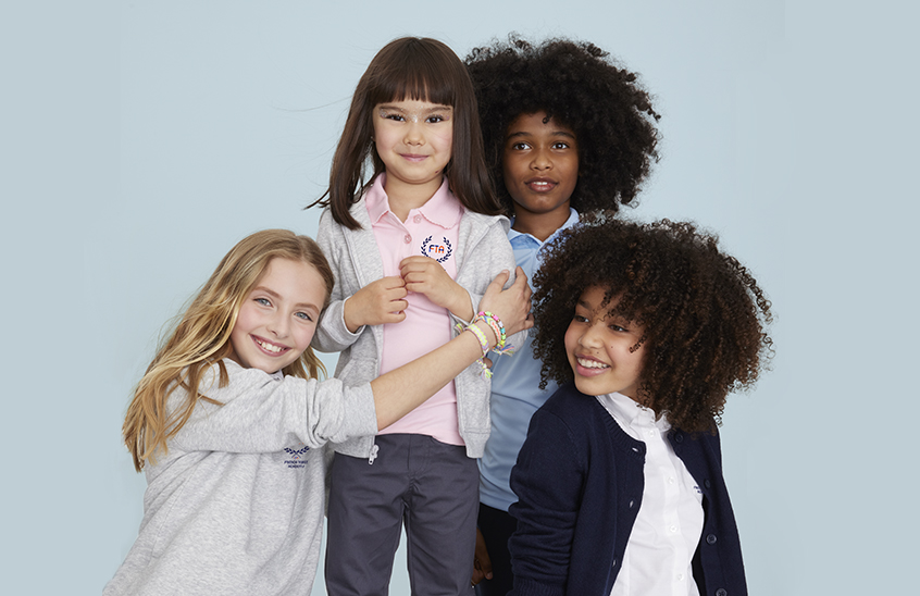 a group of four kids wearing embroidered school uniforms